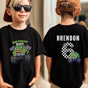 May include: Black t-shirt with a green monster truck graphic and the words "BIRTHDAY BOY" on the front. The back shows the name "BRENDON" and the number "6" in a chequered pattern, plus a smaller monster truck graphic.