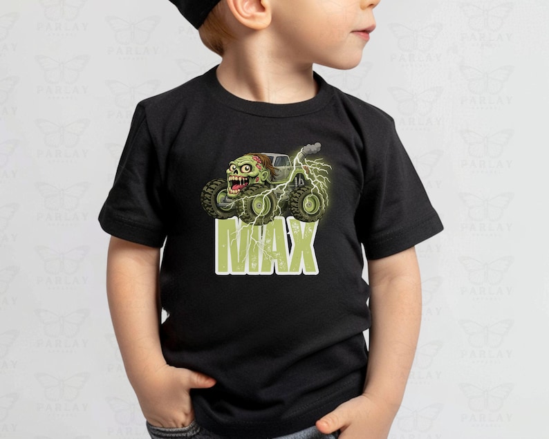 May include: Black t-shirt featuring a monster truck with a zombie driver, lightning bolts, and the name "MAX" in green block letters. The graphic is detailed with green, brown, and gray tones, creating a fun, cartoonish design.
