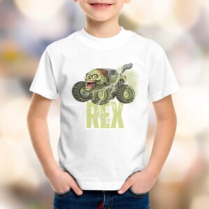 May include: White t-shirt featuring a cartoon monster truck with a zombie driver, green and gray color scheme, and the name "REX" in green block letters. The truck has large tires and lightning bolts.