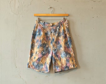 May include: A pair of blue, pink and yellow patterned shorts with a button fastening. The shorts have a high waist and a relaxed fit.