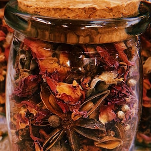 May include: A glass jar filled with dried rose petals, star anise, and other spices. The jar has a cork lid.