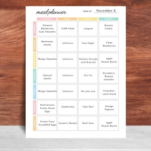 May include: A weekly meal planner with the title "meal planner" at the top. The planner is organized by day and meal, with breakfast, lunch, dinner, and snack sections. The week of November 6 is displayed. The planner includes meal ideas like oatmeal, lasagna, and apple peanut butter.