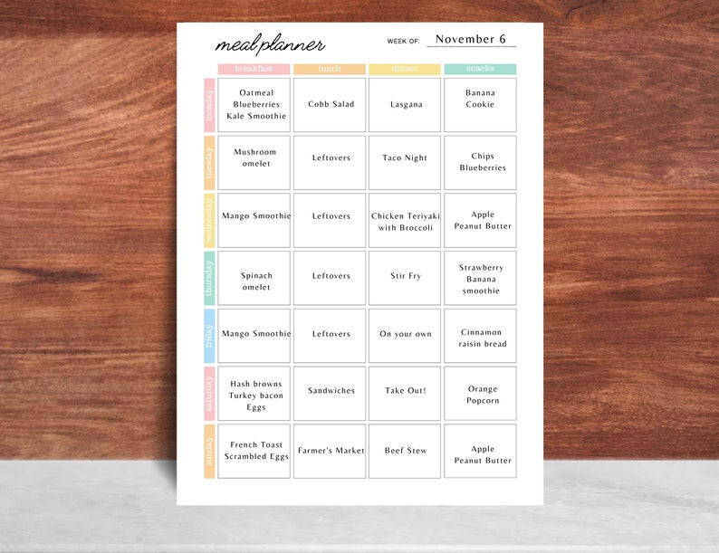May include: A weekly meal planner with the title "meal planner" at the top. The planner is organized by day and meal, with breakfast, lunch, dinner, and snack sections. The week of November 6 is displayed. The planner includes meal ideas like oatmeal, lasagna, and apple peanut butter.