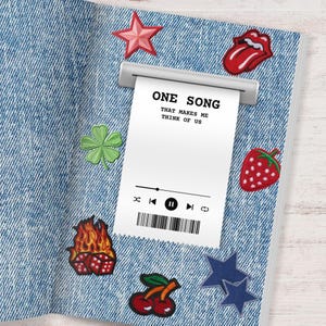 May include: A denim-textured notebook with various embroidered patches. Patches include a red star, a four-leaf clover, a strawberry, a pair of cherries, a flaming dice, a blue star, and a red tongue. A receipt-like paper reads "ONE SONG THAT MAKES ME THINK OF US".