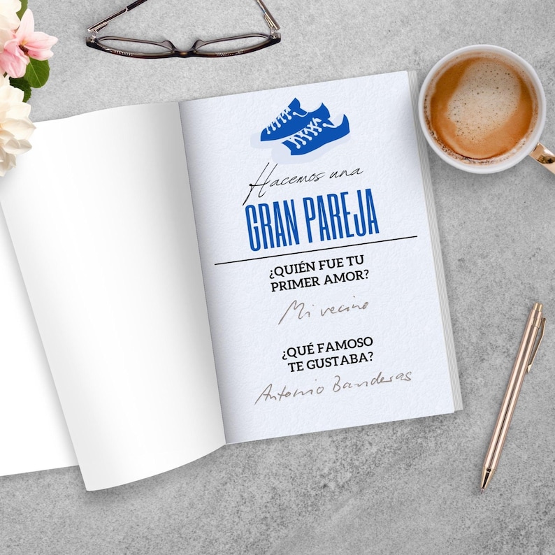 Puede incluir: Un libro abierto con el texto "Hacemos una GRAN PAREJA" en azul, junto con preguntas y respuestas. Un gr&aacute;fico de zapato azul est&aacute; en la parte superior. Una taza de caf&eacute;, gafas, un bol&iacute;grafo y flores est&aacute;n sobre la superficie gris.