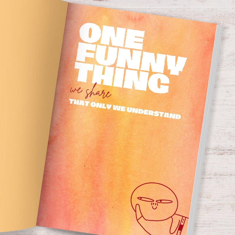 Puede incluir: Libro abierto con un fondo naranja y amarillo estilo acuarela. El texto blanco dice "ONE FUNNY THING we share THAT ONLY WE UNDERSTAND". Un personaje de dibujos animados est&aacute; dibujado en la esquina inferior derecha.