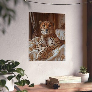 May include: A framed print featuring a cheetah with a regal demeanor, adorned with a gold necklace, resting on a bed with ornate, cream-colored bedding. The cheetah's coat is a mix of tan and black spots.