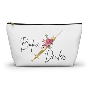 May include: White zippered pouch with a gold needle and floral design. The text "Botox Dealer" is printed in black.