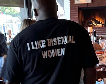 May include: A person wearing a black t-shirt with the text "I like bisexual women" printed in white.