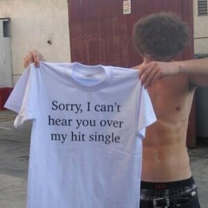 May include: White t-shirt with the text "Sorry, I can't hear you over my hit single" printed on the front.
