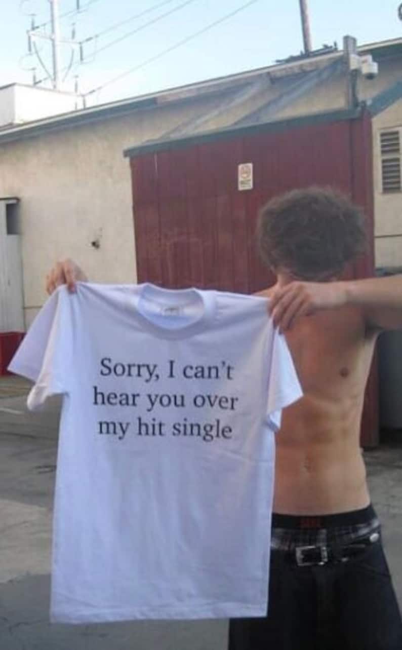 May include: White t-shirt with the text "Sorry, I can't hear you over my hit single" printed on the front.