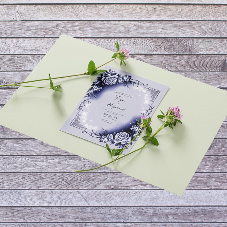 May include: A wedding invitation with a blue and white floral design. The invitation features a wreath of roses and vines with a white background and silver glitter accents. The text "Faye & Hayward" is printed in a script font at the top of the invitation.