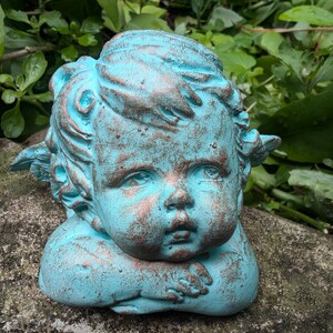 May include: A turquoise blue cherub statue with wings, a cherubic face, and a distressed finish.