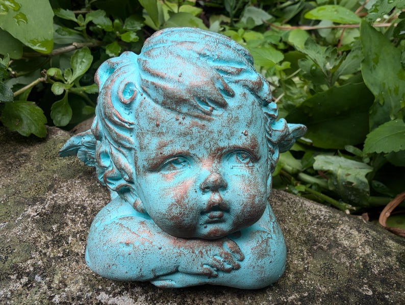 May include: A turquoise blue cherub statue with wings, a cherubic face, and a distressed finish.