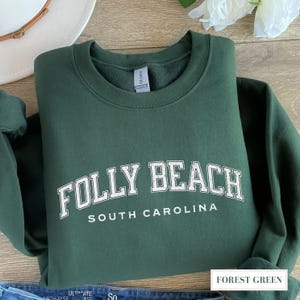 May include: Forest green sweatshirt with white text that reads "Folly Beach South Carolina".