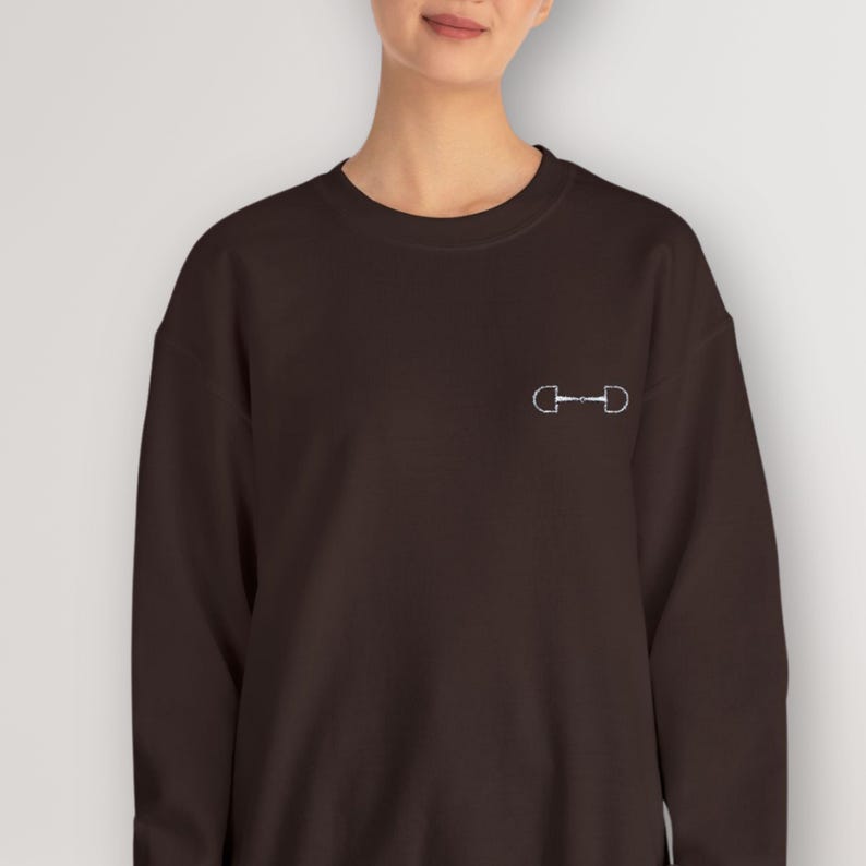 May include: A dark brown sweatshirt with a white equestrian bit design on the front.