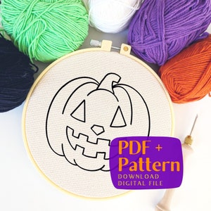 以下が含まれることがあります： 白い刺繍枠に、黒い線で描かれたジャック・オ・ランタンの絵が描かれているクローズアップ。枠の周りは、緑、紫、オレンジ、黒など、さまざまな色の糸玉で囲まれている。画像には木製の針も写っている。テキスト「PDF + Pattern」は、紫色の背景にオレンジと白で書かれている。
