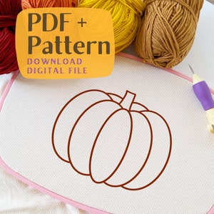 May include: A digital download PDF pattern for a simple pumpkin embroidery design. The pattern is shown on a white Aida cloth with a pink embroidery hoop. The image also includes balls of yarn in orange, yellow, and brown.