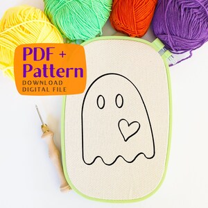 May include: A white embroidery hoop with a black line drawing of a ghost with two eyes and a heart. The text "PDF + Pattern DOWNLOAD DIGITAL FILE" is on a orange background.