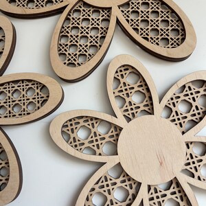 May include: Three wooden flower-shaped wall decor pieces with a woven pattern. The flowers are light brown and have a natural wood finish.
