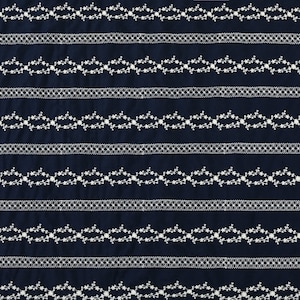 May include: A navy blue fabric with white embroidered floral patterns. The fabric has a repeating pattern of delicate floral vines with small white flowers.