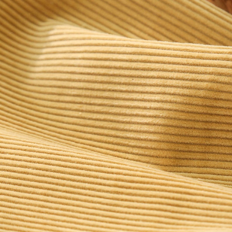 May include: Close-up of a light brown corduroy fabric with a subtle texture. The fabric has a smooth, soft feel and a slightly raised, ribbed pattern.