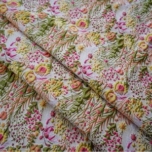 May include: White fabric with a floral pattern in shades of pink, yellow, and green. The fabric has a textured, raised design.