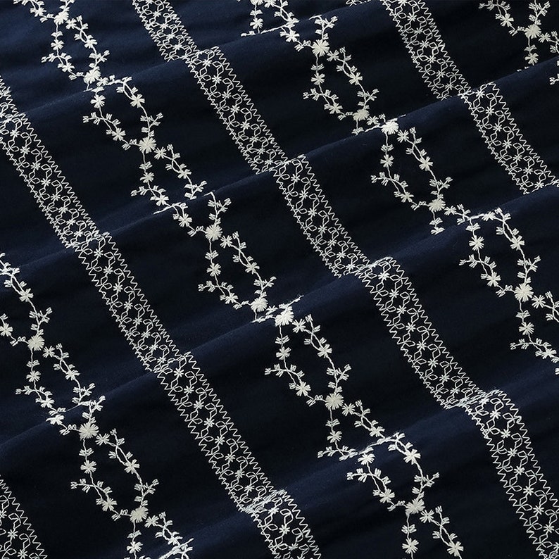 May include: Navy blue fabric with white embroidered floral patterns in a striped design.
