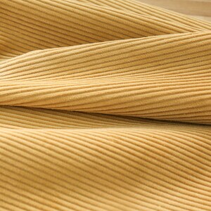 May include: Close-up of a soft, yellow corduroy fabric with a subtle ribbed texture.