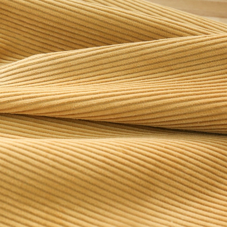 May include: Close-up of a soft, yellow corduroy fabric with a subtle ribbed texture.