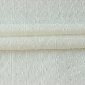 May include: White cotton fabric with a small dot pattern and vertical stripes. The fabric is folded in thirds.