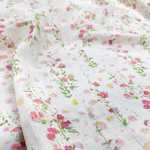 May include: White fabric with a pink floral print. The fabric features small pink flowers and larger pink flowers with green stems.