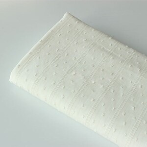 May include: White cotton fabric with a textured pattern of small dots and horizontal stripes.