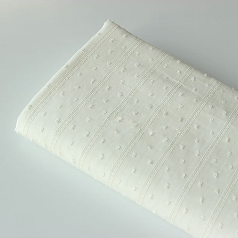 May include: White cotton fabric with a textured pattern of small dots and horizontal stripes.