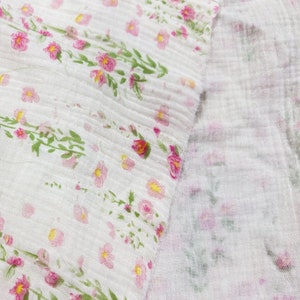 May include: White fabric with a pink floral pattern. The fabric is sheer and has a slightly wrinkled texture.