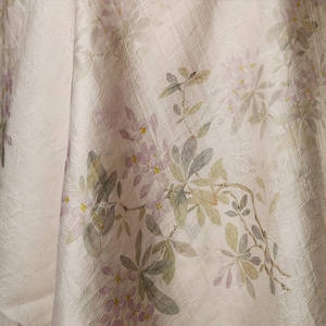 Pu&ograve; includere: Un tessuto bianco con un delicato motivo floreale. I fiori sono di un rosa pallido e le foglie di un verde chiaro. Il tessuto ha una texture sottile.