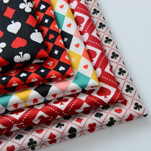 Könnte beinhalten: Ein Stapel aus sechs Stoffquadraten mit verschiedenen Mustern, die Spielkartensymbole zeigen. Die Muster umfassen rote Herzen, schwarze Kreuzchen, schwarze Pik und rote Karo. Die Stoffe sind in verschiedenen Farben, darunter Rot, Schwarz, Weiß, Gelb und Türkis.