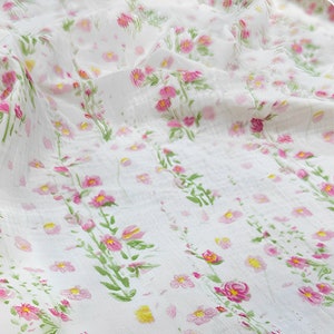 May include: White sheer fabric with a delicate floral pattern in shades of pink and green. The fabric has a subtle texture and a soft, flowing drape.