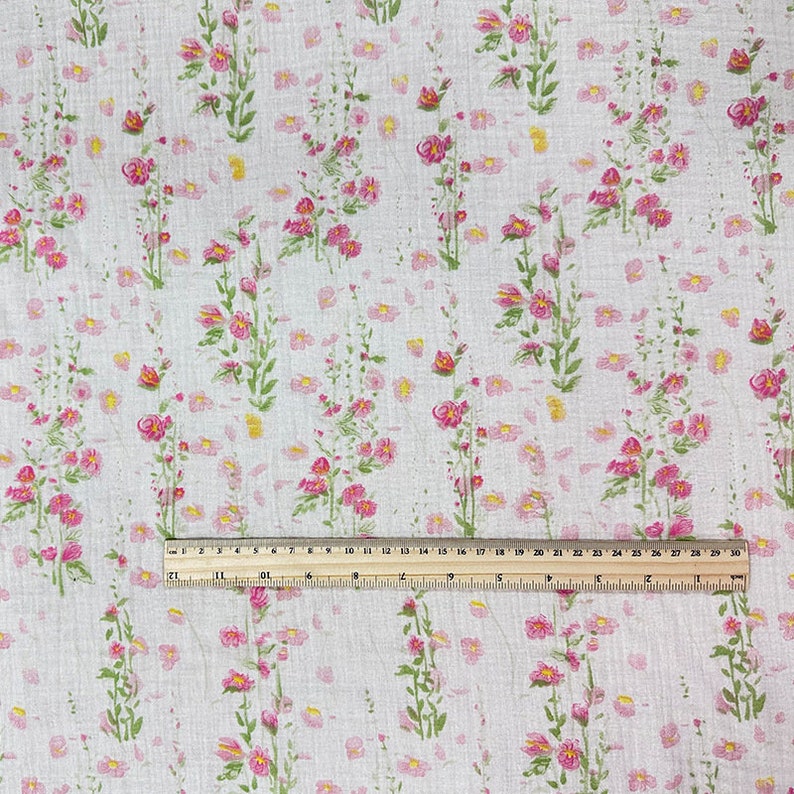 May include: White fabric with a pink and green floral pattern. The fabric is measured with a ruler that shows 30 inches.