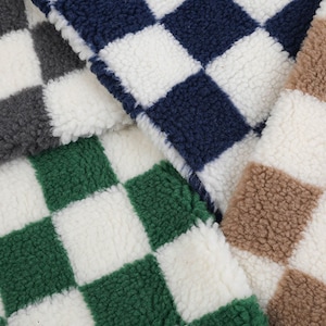 Op de afbeelding: Close-up van vier stofstalen met een geruit patroon. De stalen zijn in de kleuren grijs, donkerblauw, groen en bruin.