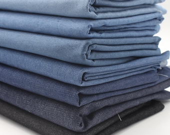 May include: A stack of denim fabric in various shades of blue, from light to dark.