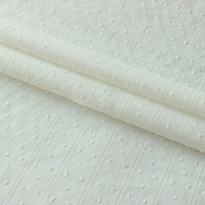 May include: White cotton fabric with a textured pattern of small dots and vertical stripes.