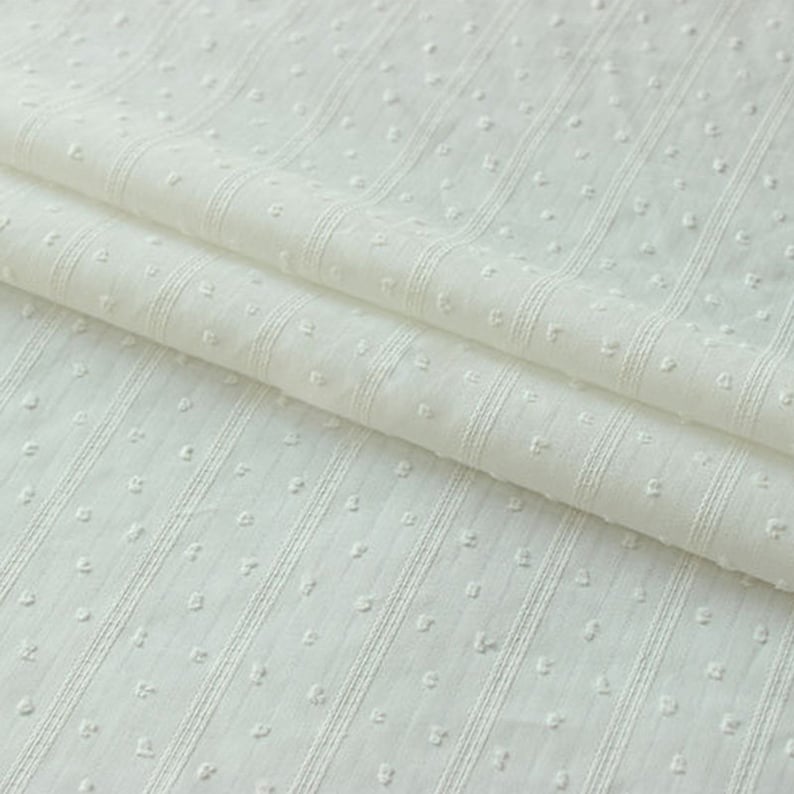 May include: White cotton fabric with a textured pattern of small dots and vertical stripes.