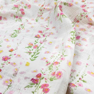 May include: White fabric with a pink and green floral print. The fabric has a textured, crinkled look.