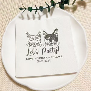 Pode incluir: Guardanapo de papel branco com uma ilustração em preto e branco de dois gatos. O texto "Let's Party!" é impresso abaixo dos gatos, seguido de "LOVE, TORREYA & TOMOKA 09-01-2024".