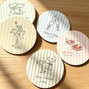 Pode incluir: Cinco bases para copos redondas com padrões de riscas pastel em amarelo, azul, verde e rosa. Cada base apresenta ilustrações de linhas pretas de flutes de champanhe ou copos de cocktail, com nomes e datas personalizados impressos a preto.