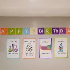 May include: A wall decorated with colorful science-themed birthday decorations. The decorations feature the periodic table of elements and science puns. The text on the wall reads "HAPPY BIRTHDAY".