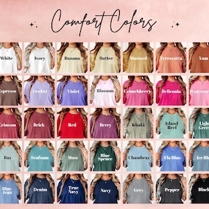 May include: A color chart featuring a variety of Comfort Colors t-shirts. The image displays a range of colors, including white, ivory, red, blue, and black, with each color labeled. The text "Comfort Colors" is at the top.