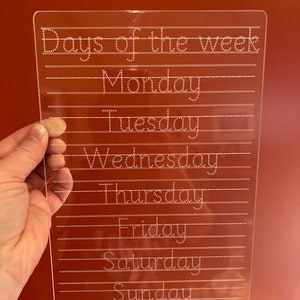 Könnte beinhalten: Ein transparentes Trockenlöschbrett aus Kunststoff mit gepunkteten Linien und den Worten "Days of the week" und den darunter aufgeschriebenen Wochentagen.