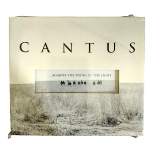 May include: A white CD case with the band name "CANTUS" printed in black letters. The title of the album is "...AGAINST THE DYING OF THE LIGHT" printed in black letters on a white background.